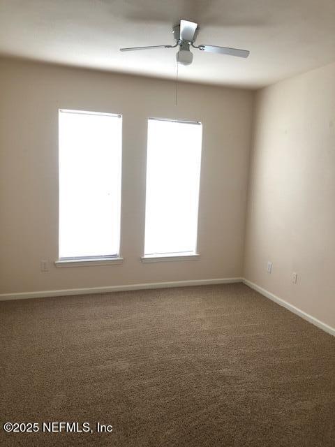 empty room featuring ceiling fan, a healthy amount of sunlight, and carpet floors