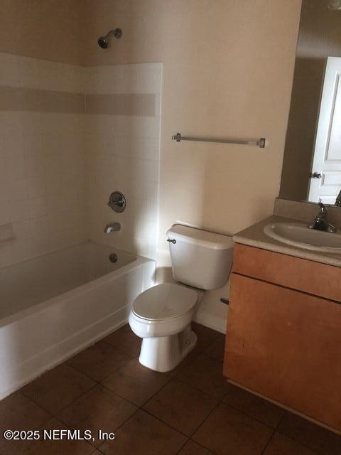 full bathroom with tile patterned flooring, tiled shower / bath, vanity, and toilet