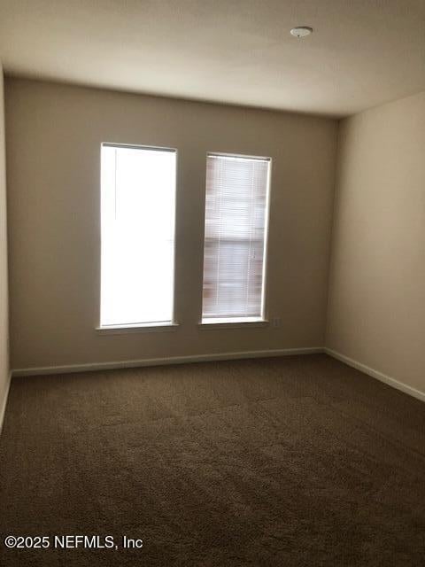 spare room with dark carpet