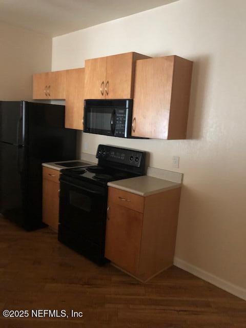 kitchen featuring dark hardwood / wood-style flooring and black appliances