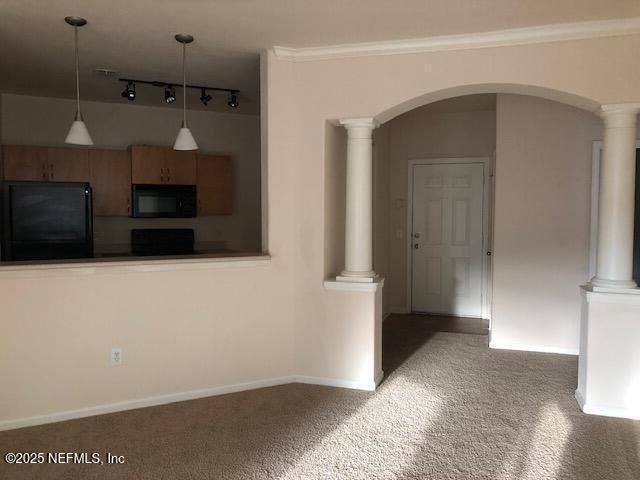 interior space featuring decorative light fixtures, decorative columns, dark colored carpet, black appliances, and crown molding