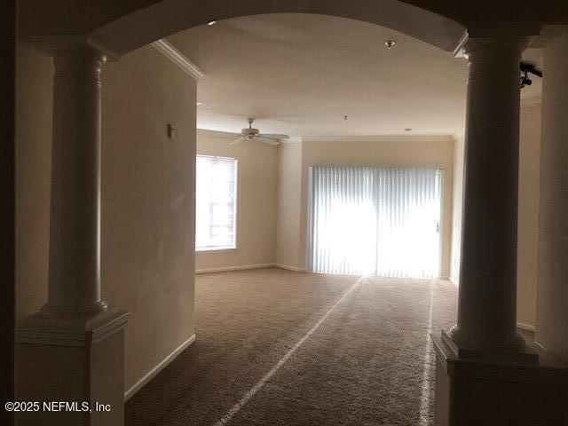 spare room with carpet flooring, ornamental molding, ceiling fan, and ornate columns