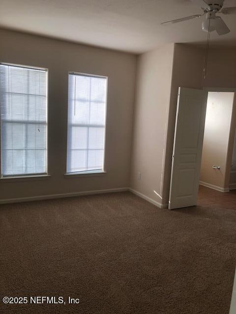 carpeted spare room featuring ceiling fan