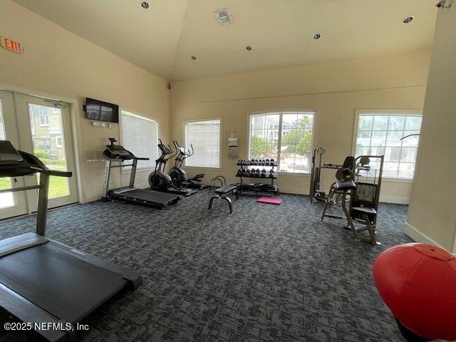 workout area with high vaulted ceiling and dark carpet