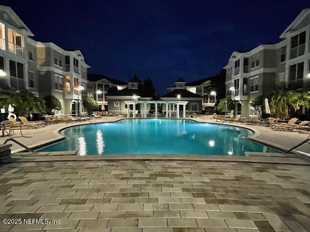 pool at night featuring a patio