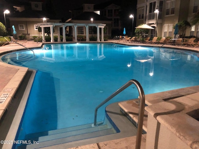 pool at twilight featuring a pergola