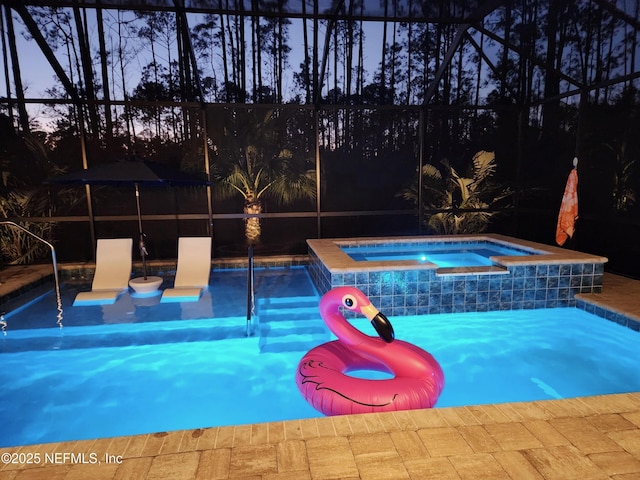 pool at dusk with an in ground hot tub and a lanai