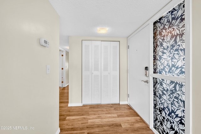 corridor featuring a textured ceiling and light hardwood / wood-style flooring