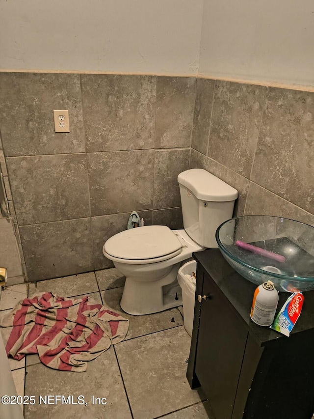 bathroom featuring toilet, tile patterned floors, tile walls, and vanity