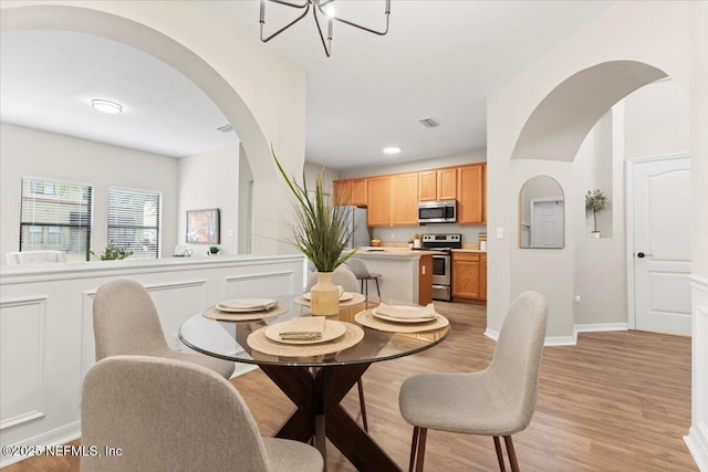 dining space with a chandelier and light hardwood / wood-style floors