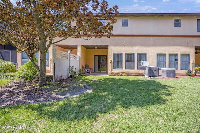 rear view of property featuring cooling unit, a yard, and ceiling fan