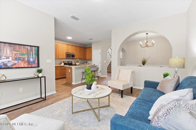 living room with sink, a chandelier, and light hardwood / wood-style flooring