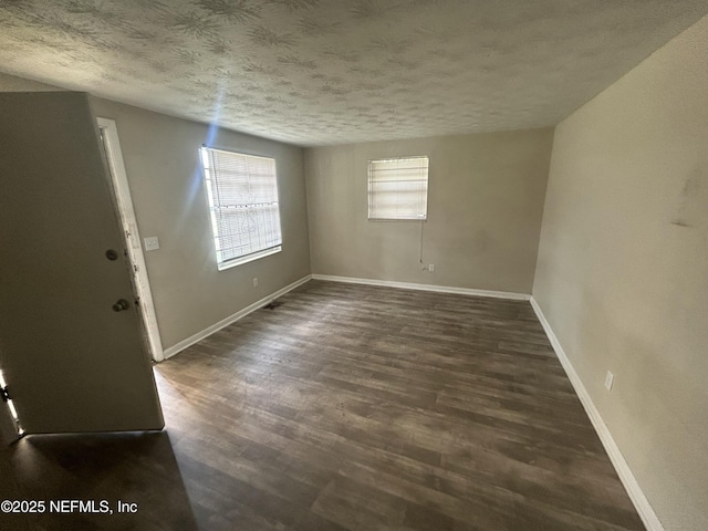 empty room with a textured ceiling and dark hardwood / wood-style flooring