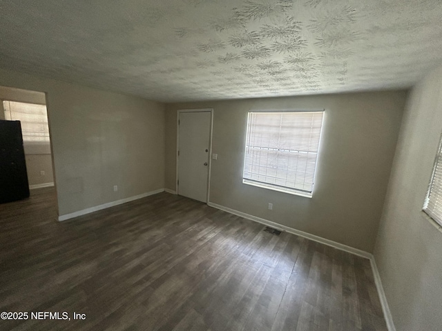 spare room with dark hardwood / wood-style floors and a textured ceiling