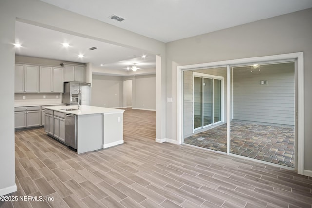 kitchen featuring light hardwood / wood-style floors, gray cabinets, stainless steel appliances, a kitchen island with sink, and sink