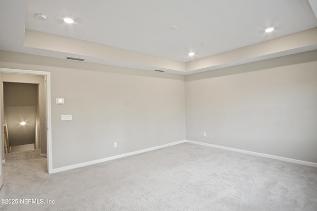 unfurnished room with light carpet and a tray ceiling