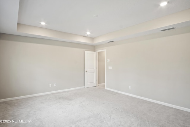 empty room with carpet and a raised ceiling