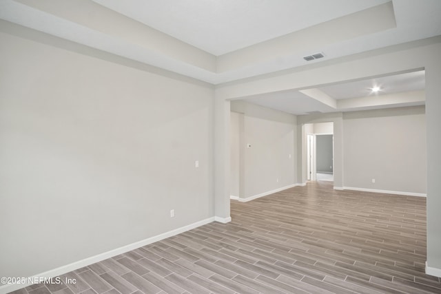 empty room with light hardwood / wood-style floors and a tray ceiling