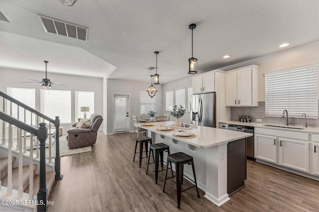 kitchen featuring stainless steel appliances, backsplash, white cabinets, and a center island