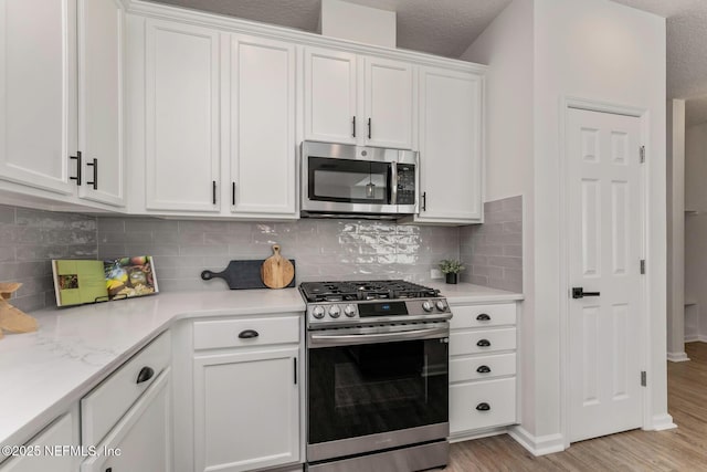 kitchen featuring a textured ceiling, white cabinetry, stainless steel appliances, tasteful backsplash, and light hardwood / wood-style flooring