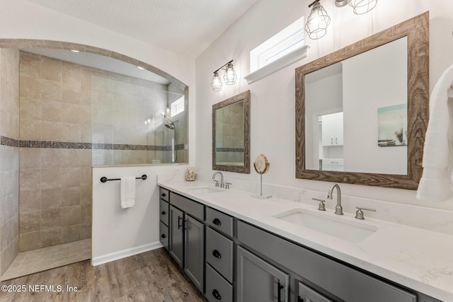 bathroom with vanity, a textured ceiling, tiled shower, and hardwood / wood-style floors