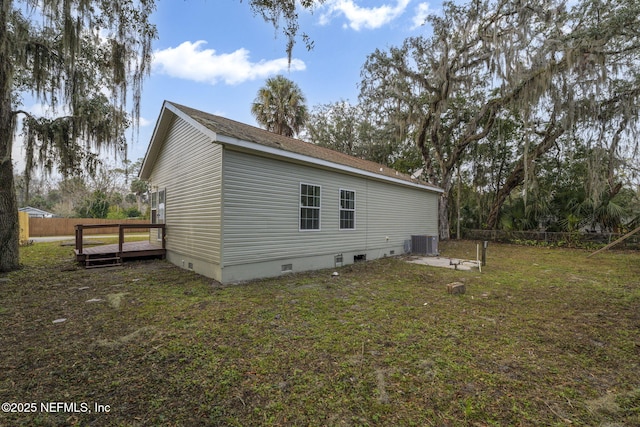 view of side of property with a yard, a wooden deck, and cooling unit