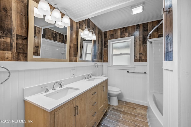 full bathroom featuring toilet, wood walls, vanity, and bathtub / shower combination