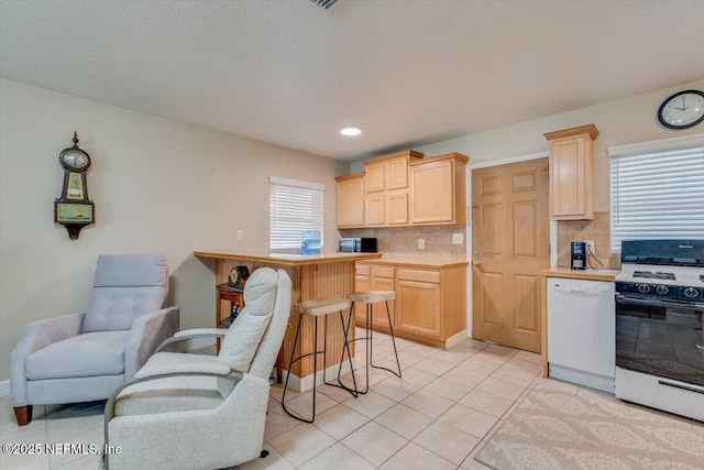 kitchen featuring white appliances, light brown cabinetry, tasteful backsplash, and a wealth of natural light