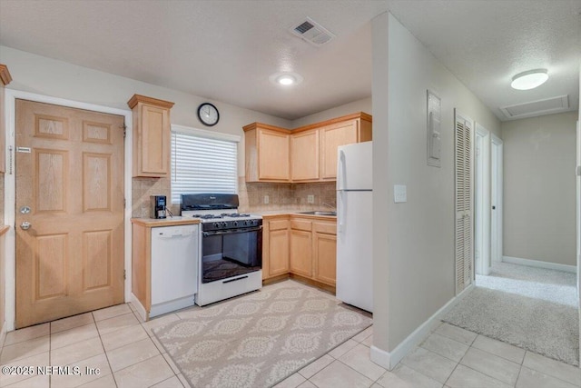 kitchen with white appliances, a textured ceiling, light brown cabinetry, light tile patterned floors, and backsplash