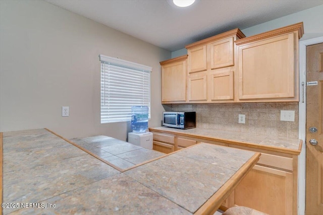 kitchen with light brown cabinets, tile counters, backsplash, and kitchen peninsula