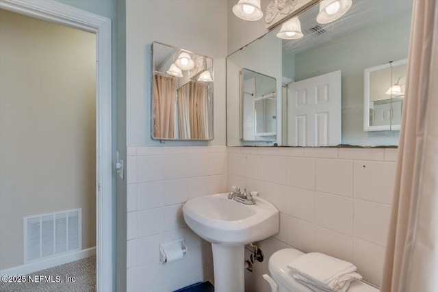 bathroom featuring tile walls and toilet