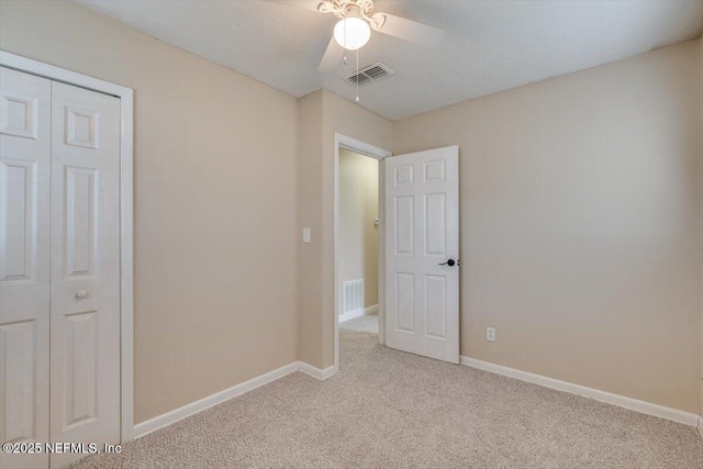 unfurnished bedroom featuring ceiling fan, a closet, and light carpet