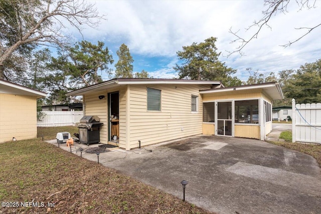 rear view of property featuring a sunroom and a patio area