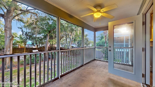 unfurnished sunroom with ceiling fan