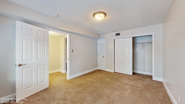 unfurnished bedroom featuring a textured ceiling and light carpet