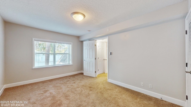 empty room with light carpet and a textured ceiling