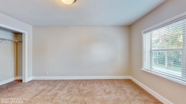 unfurnished bedroom with light carpet, a closet, and a textured ceiling