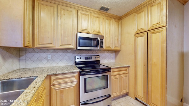 kitchen featuring decorative backsplash, light tile patterned flooring, light stone countertops, appliances with stainless steel finishes, and light brown cabinets