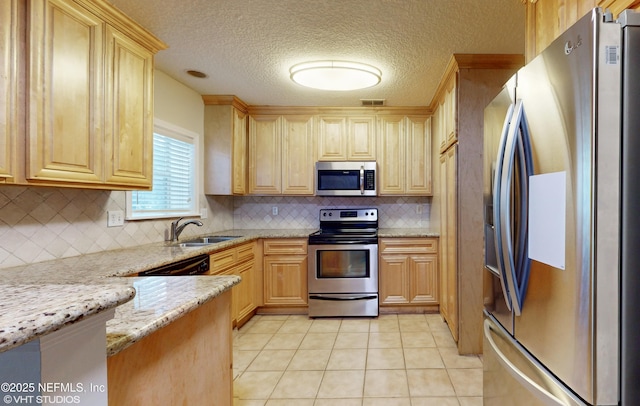 kitchen with sink, light stone countertops, light brown cabinets, stainless steel appliances, and light tile patterned floors