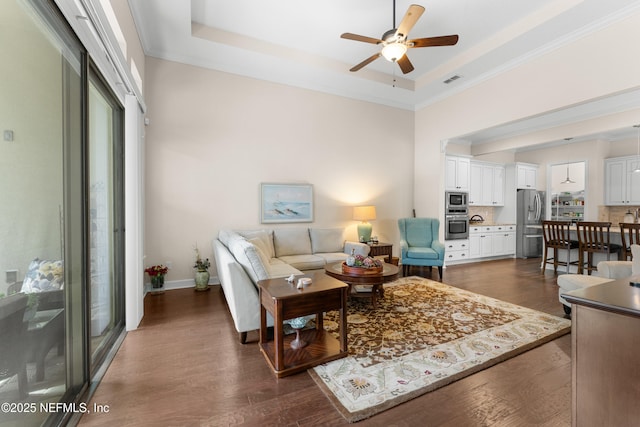 living room with ceiling fan, ornamental molding, a raised ceiling, and dark hardwood / wood-style floors