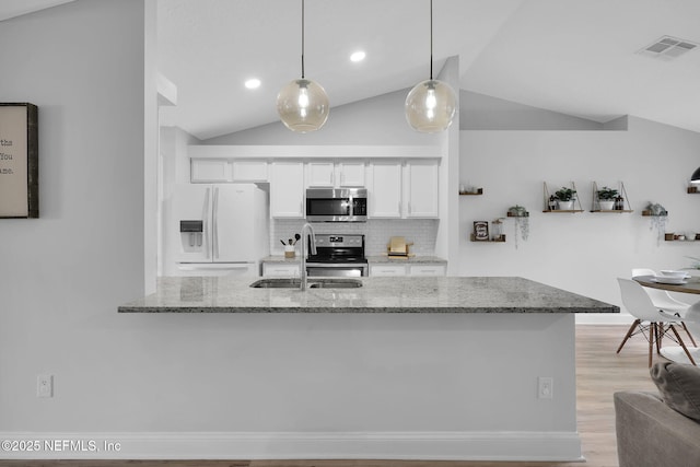 kitchen with light stone countertops, vaulted ceiling, decorative light fixtures, white cabinets, and appliances with stainless steel finishes