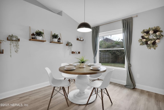 dining room with light hardwood / wood-style floors, vaulted ceiling, and a wealth of natural light