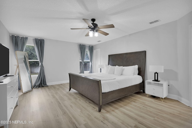 bedroom with a textured ceiling, ceiling fan, and light hardwood / wood-style flooring