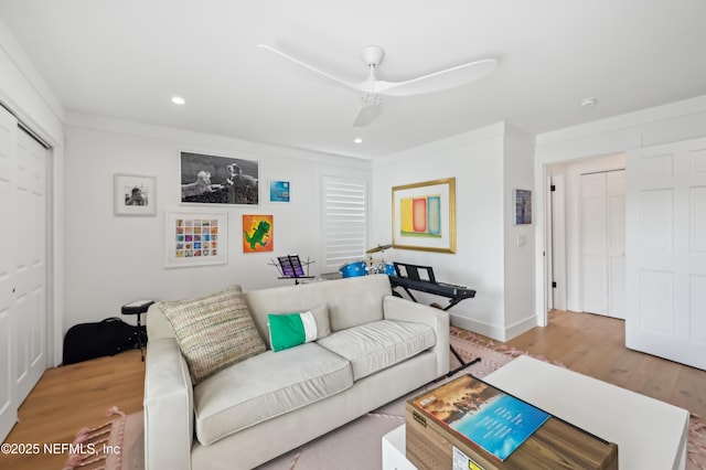 living room featuring ornamental molding, ceiling fan, and light wood-type flooring