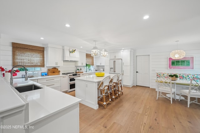 kitchen with pendant lighting, white cabinetry, double oven range, and sink