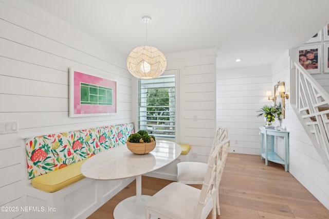 dining area featuring breakfast area, wooden walls, and light hardwood / wood-style flooring