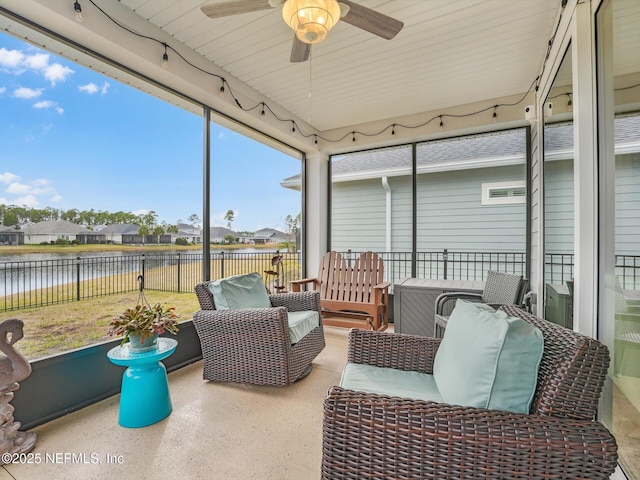 sunroom featuring ceiling fan and a water view