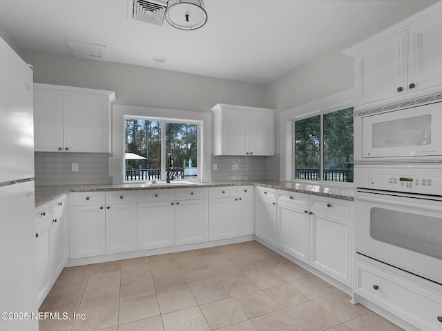 kitchen featuring decorative backsplash, sink, and white cabinets