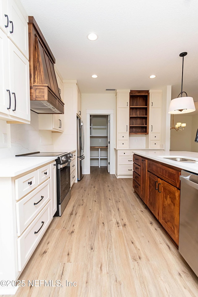 kitchen with custom exhaust hood, stainless steel appliances, pendant lighting, and white cabinets