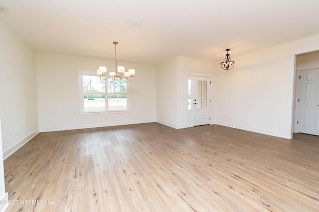 unfurnished room featuring an inviting chandelier and light hardwood / wood-style flooring